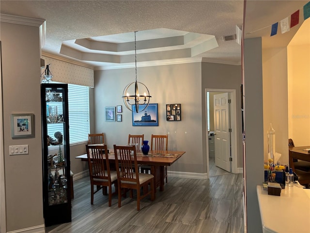 dining room featuring a textured ceiling, crown molding, a chandelier, and a tray ceiling