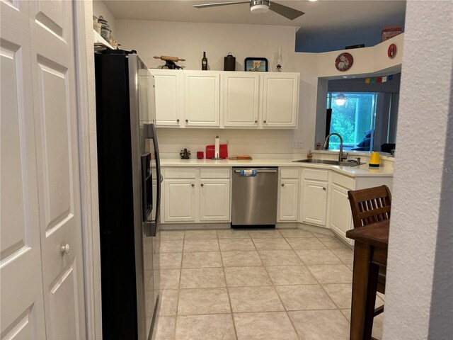 kitchen featuring appliances with stainless steel finishes, sink, ceiling fan, white cabinets, and light tile patterned flooring