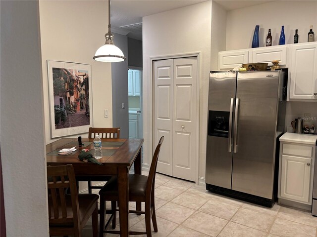 kitchen with decorative light fixtures, white cabinets, light tile patterned floors, and stainless steel fridge with ice dispenser