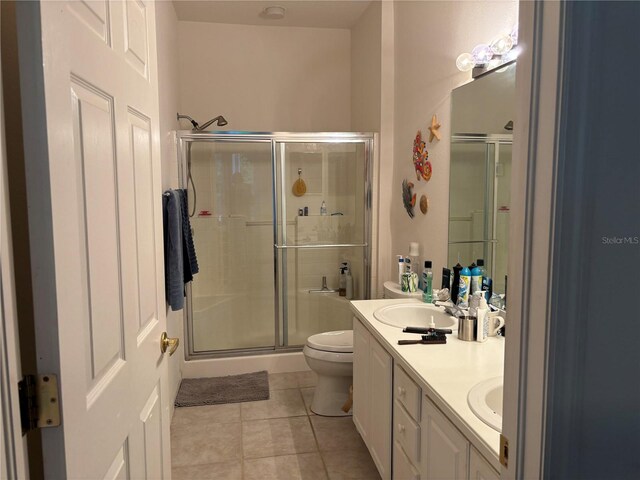 bathroom featuring a shower with door, vanity, toilet, and tile patterned flooring