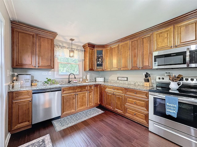 kitchen with appliances with stainless steel finishes, crown molding, dark wood-type flooring, sink, and light stone counters