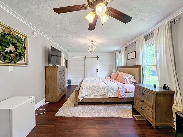 bedroom featuring a textured ceiling, dark hardwood / wood-style flooring, crown molding, a barn door, and ceiling fan