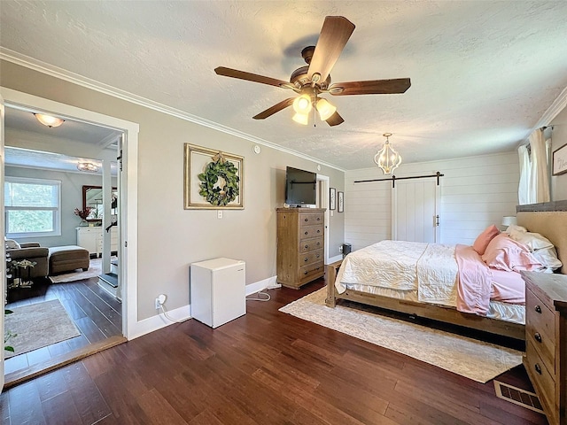 bedroom with a textured ceiling, dark hardwood / wood-style flooring, ornamental molding, a barn door, and ceiling fan