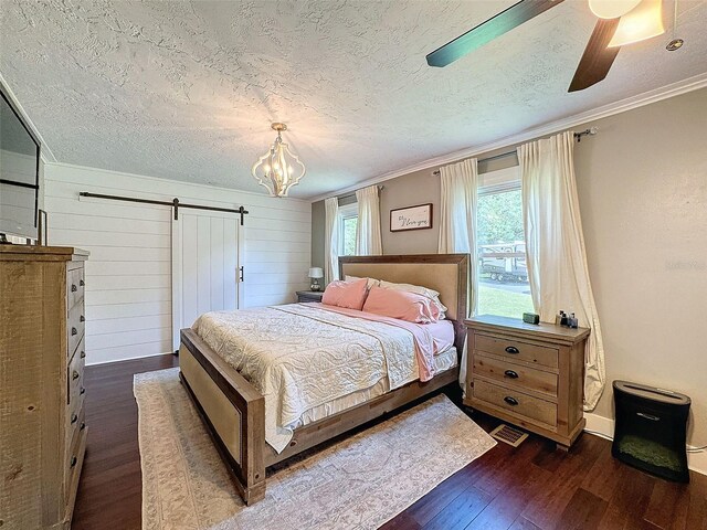 bedroom with crown molding, a textured ceiling, wood walls, dark hardwood / wood-style flooring, and a barn door