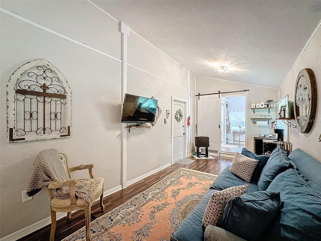 living room with vaulted ceiling, a textured ceiling, hardwood / wood-style flooring, and a barn door