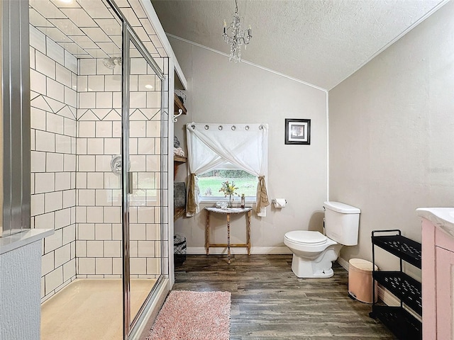 bathroom featuring hardwood / wood-style flooring, a shower with door, toilet, lofted ceiling, and vanity