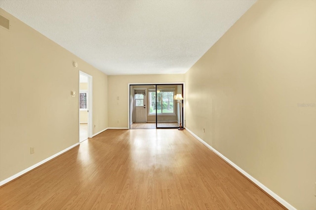 unfurnished room with light wood-type flooring and a textured ceiling