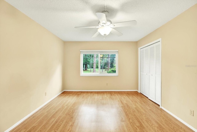 unfurnished bedroom with a closet, a textured ceiling, ceiling fan, and light hardwood / wood-style floors