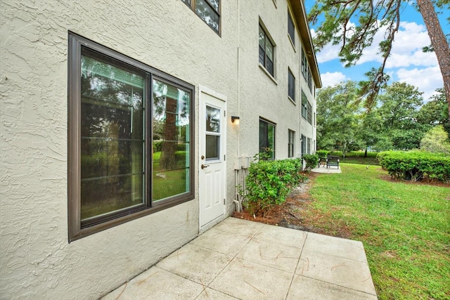 view of side of property featuring a patio area and a lawn