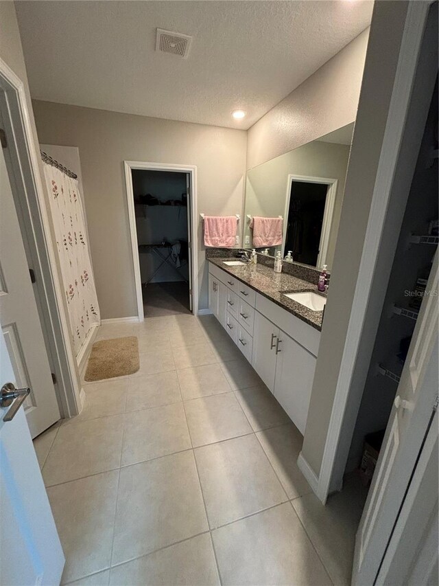 bathroom with tile patterned flooring, a textured ceiling, and vanity