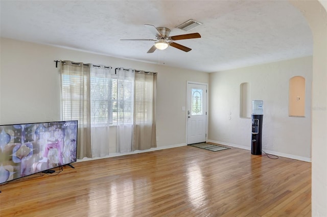 unfurnished living room featuring ceiling fan, light hardwood / wood-style floors, and a textured ceiling