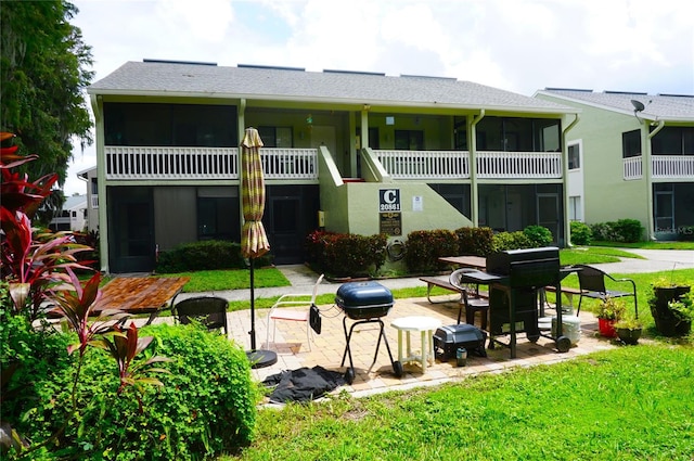 rear view of property with a yard, a patio, and a balcony