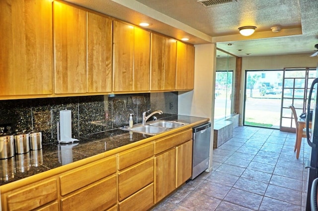 kitchen with tile patterned floors, sink, stainless steel dishwasher, decorative backsplash, and a textured ceiling