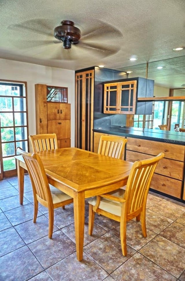 dining area featuring tile patterned flooring, ceiling fan, and a textured ceiling