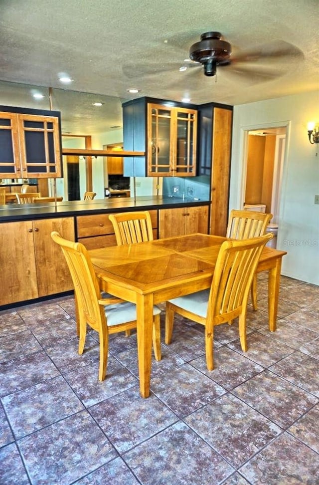 dining area with a textured ceiling, dark tile patterned floors, and ceiling fan