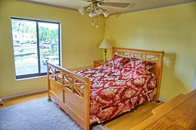 bedroom with crown molding, a textured ceiling, hardwood / wood-style floors, and ceiling fan