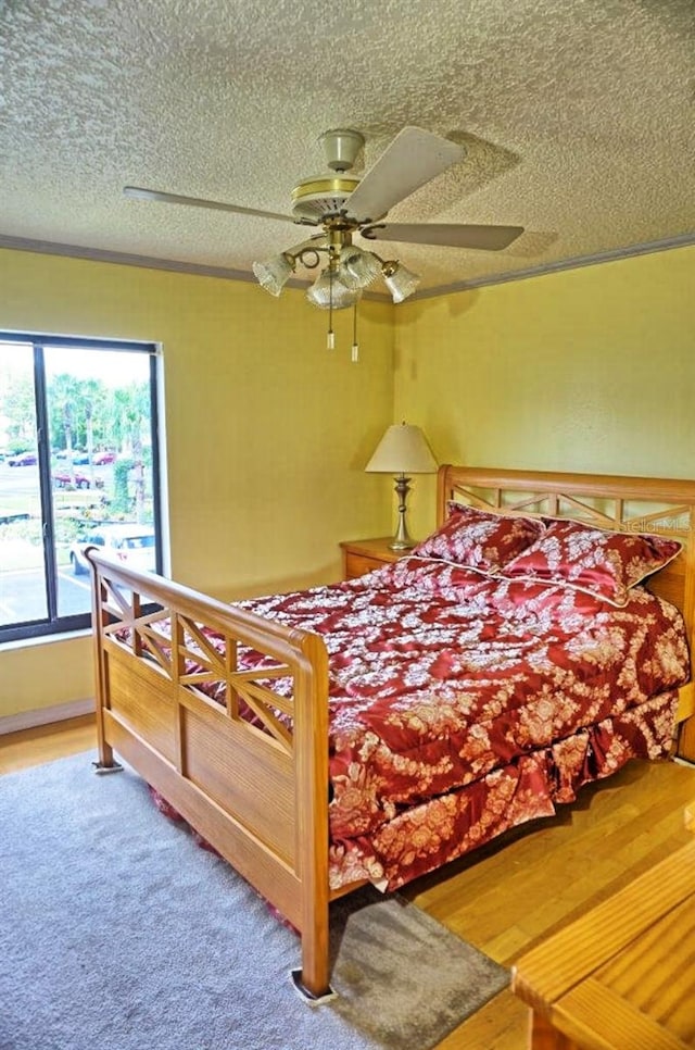 bedroom featuring ceiling fan, hardwood / wood-style flooring, and a textured ceiling