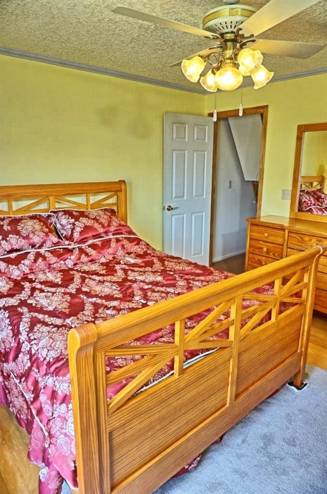 carpeted bedroom featuring ceiling fan and a textured ceiling