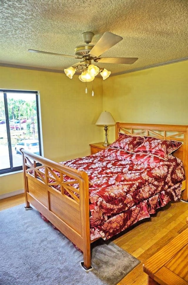 bedroom with a textured ceiling, ceiling fan, and wood-type flooring