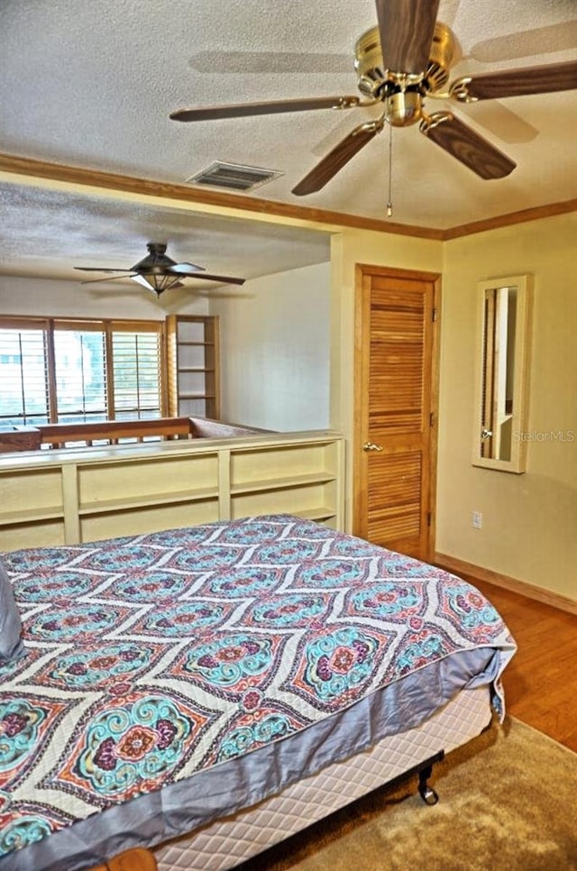 bedroom with ornamental molding, a textured ceiling, wood-type flooring, and ceiling fan