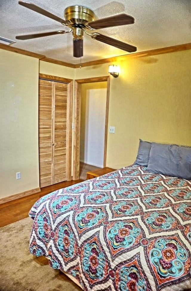 bedroom featuring a closet, ceiling fan, wood-type flooring, and a textured ceiling