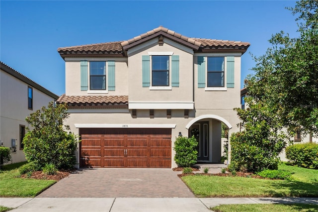 mediterranean / spanish-style home featuring a garage and a front lawn