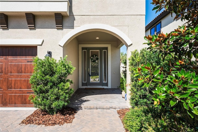 doorway to property with stucco siding and a garage