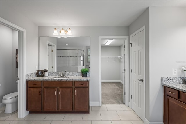 bathroom with vanity, baseboards, a stall shower, tile patterned flooring, and toilet