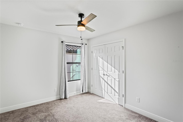 unfurnished bedroom featuring a closet, baseboards, carpet floors, and ceiling fan