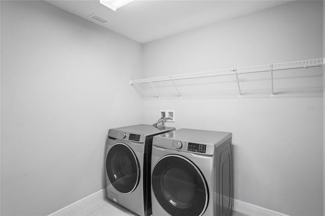 laundry area featuring visible vents, light tile patterned floors, baseboards, laundry area, and washing machine and clothes dryer