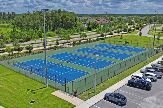 view of tennis court with a yard and fence