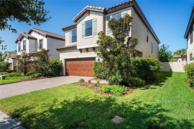 mediterranean / spanish home featuring decorative driveway, a garage, stucco siding, and fence