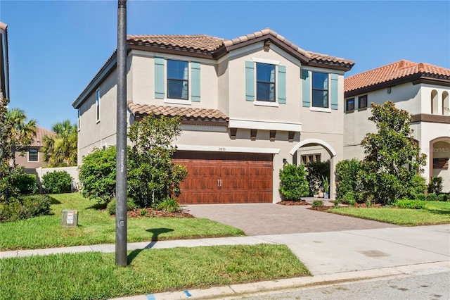 mediterranean / spanish-style home with a tile roof, decorative driveway, an attached garage, and stucco siding