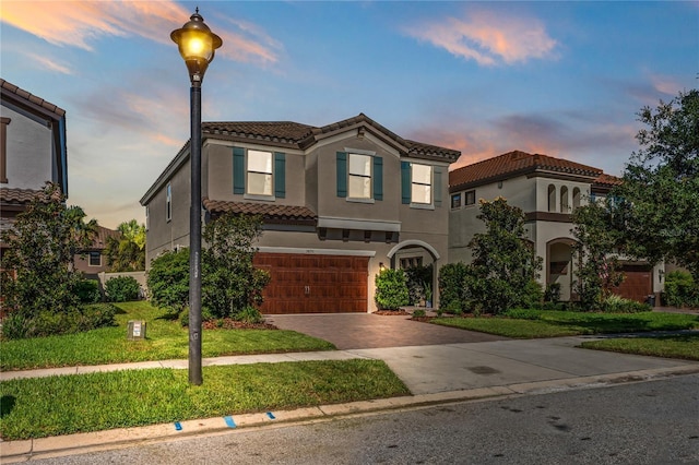 mediterranean / spanish-style house featuring stucco siding, a front lawn, decorative driveway, a garage, and a tiled roof