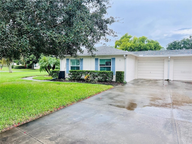 view of front of home with an attached garage, roof with shingles, concrete driveway, and a front lawn