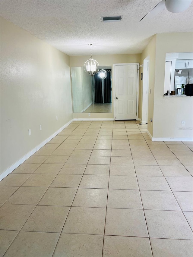 interior space featuring a textured ceiling, a notable chandelier, and light tile patterned flooring