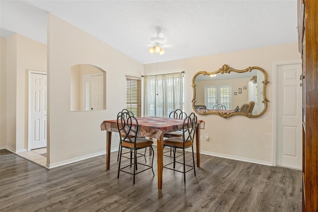 dining room with lofted ceiling, a textured ceiling, ceiling fan, and dark wood-type flooring