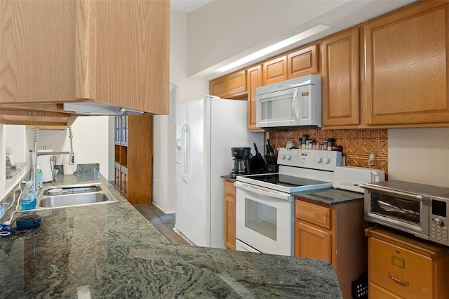 kitchen featuring white appliances, decorative backsplash, dark stone countertops, and sink