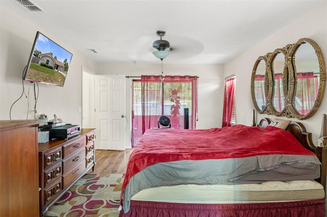 bedroom with ceiling fan, a textured ceiling, and wood-type flooring