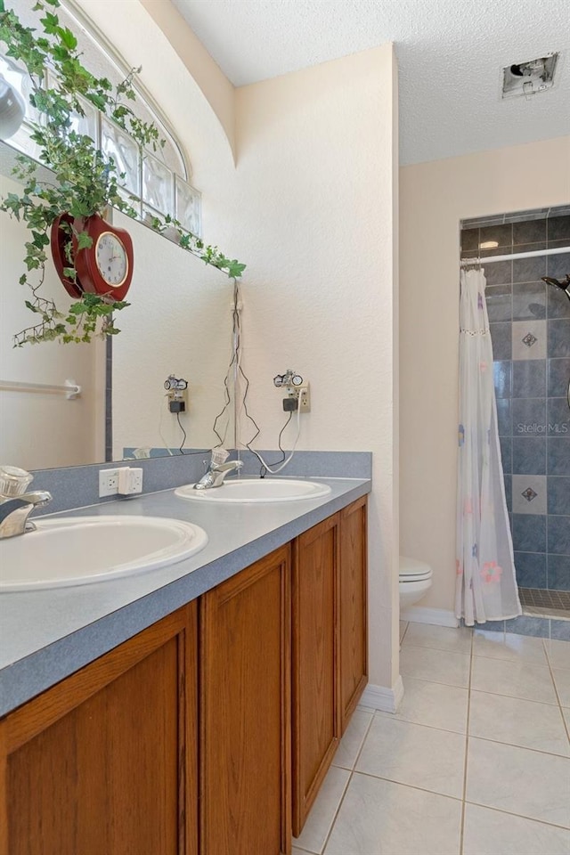 bathroom featuring toilet, a textured ceiling, walk in shower, tile patterned flooring, and vanity