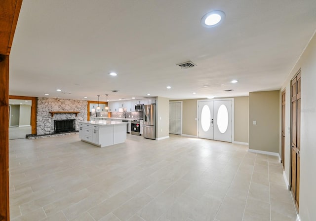 unfurnished living room with a stone fireplace and sink