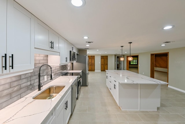 kitchen featuring light stone counters, sink, decorative light fixtures, and white cabinets