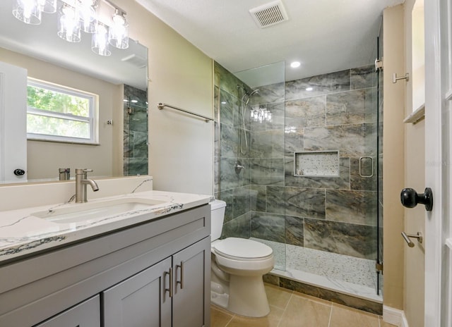 bathroom with vanity, toilet, a shower with shower door, and tile patterned flooring