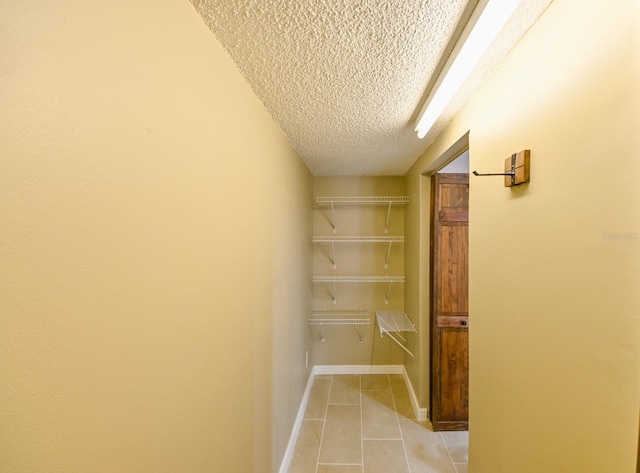 corridor featuring light tile patterned flooring and a textured ceiling