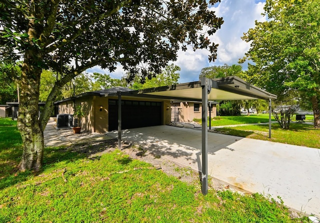 view of front of home with a garage, a carport, cooling unit, and a front lawn