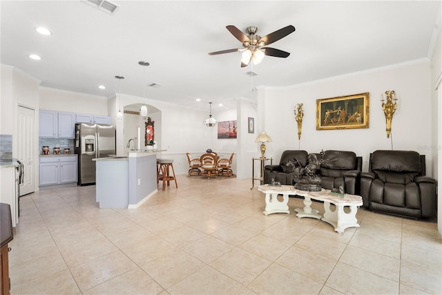 tiled living room with ornamental molding and ceiling fan