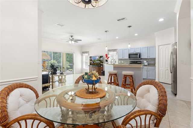 dining room with ornamental molding, light tile patterned flooring, sink, and ceiling fan