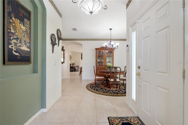 tiled entryway with a notable chandelier