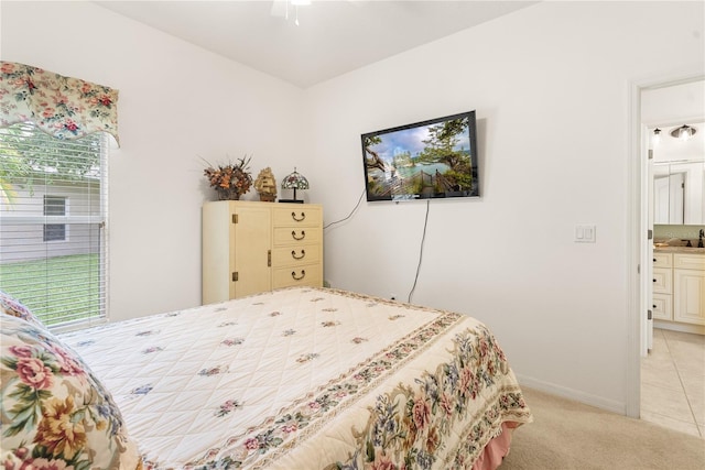 carpeted bedroom with ensuite bath, multiple windows, and ceiling fan