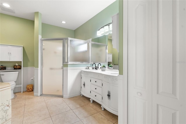 bathroom with vanity, toilet, tile patterned floors, and a shower with door